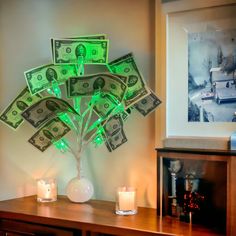 a tree made out of dollar bills sitting on top of a table next to candles