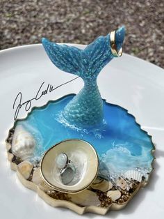 a blue mermaid tail is sitting on top of an oyster shell with shells in it