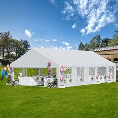 a white tent set up for a wedding reception with balloons on the grass and people standing outside