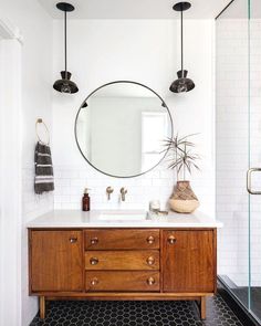 a bathroom vanity with a round mirror above it