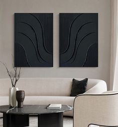 two black art pieces on the wall above a coffee table in a modern living room