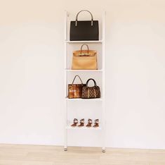 a white shelf with purses and handbags on it in front of a wall