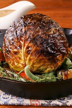 a roasting pan filled with meat and garnished with herbs on a wooden table