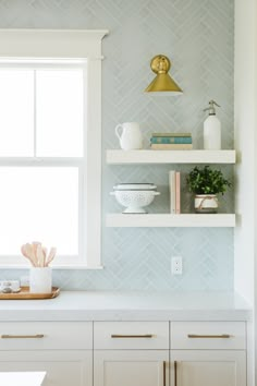 a kitchen with white cabinets and shelves filled with dishes on top of each other in front of a window