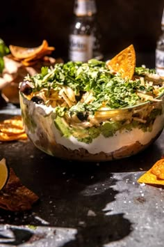 a bowl filled with food and chips on top of a table next to bottles of water