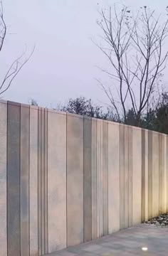 a man riding a skateboard down a sidewalk next to a tall concrete wall with trees in the background