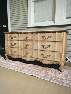 a large wooden dresser sitting on top of a rug in front of a house next to a door