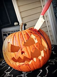 a carved pumpkin with a knife sticking out of it's mouth on top of a table