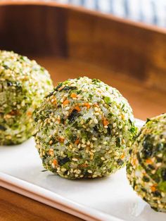 three balls of broccoli sprinkled with carrots on a white plate