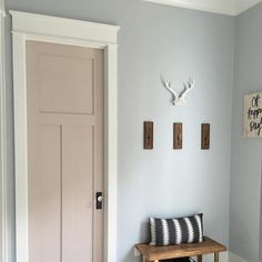 a bench in front of a door with two deer heads on the wall