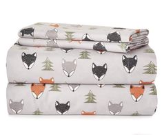 two sheets with foxes and pine trees printed on them, one is folded up to the side