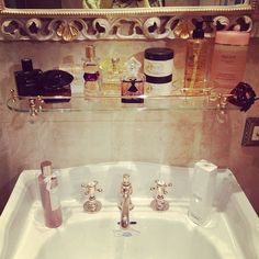 a bathroom sink with soap, lotion and other items on it in front of a mirror