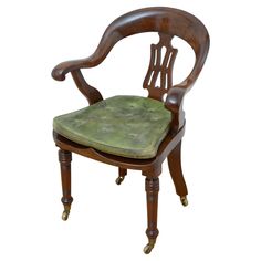 an antique wooden chair with green upholstered seat