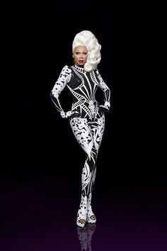 a barbie doll with white hair wearing black and white clothes, standing in front of a black background