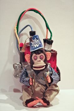 a monkey sitting on top of a table next to a bag filled with items and wires