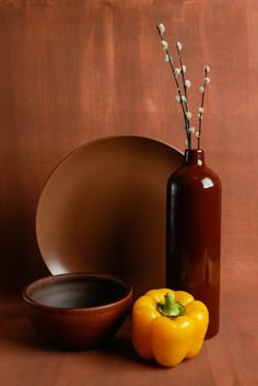 an orange bell pepper sitting next to a brown bowl