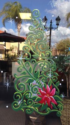 a christmas tree made out of paper with decorations on the top and bottom, sitting in front of a store window