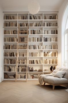 a living room filled with lots of white bookshelves next to a couch in front of a window