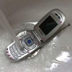 an old cell phone sitting on top of a sink with water running down it's side