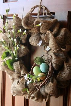 a burlock wreath with flowers and eggs on it