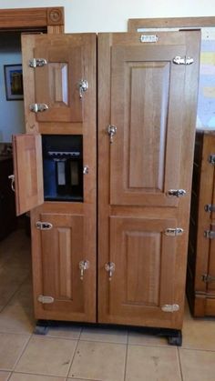 a large wooden refrigerator freezer sitting on top of a tile floor next to cabinets