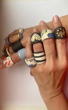 a woman's hand with five different rings on her fingers and one is holding the other