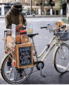 a man standing next to a bicycle with a chalkboard sign on it's back