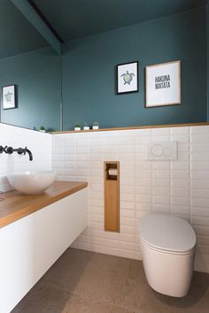 a white toilet sitting next to a sink in a bathroom under two pictures on the wall