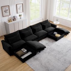 a large black sectional sofa sitting on top of a wooden floor next to a window