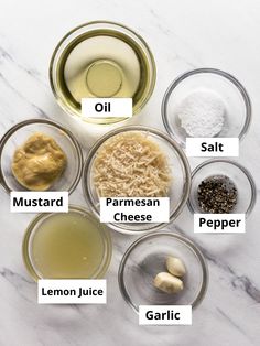 the ingredients for this recipe are shown in bowls on a marble countertop, including garlic, oil, parmesan cheese, and lemon juice