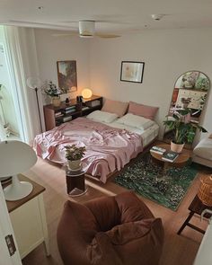 a living room filled with furniture and a large bed covered in pink sheets on top of a wooden floor