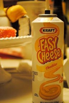 a can of easy cheese sits on a table with other food items in the background