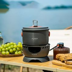 an outdoor table with grapes, bananas and a cooler on it next to the water