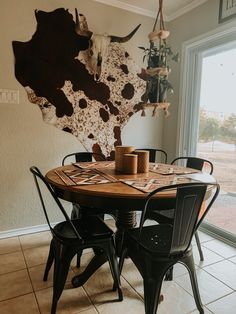 a dining room table with four chairs and a cow head on the wall