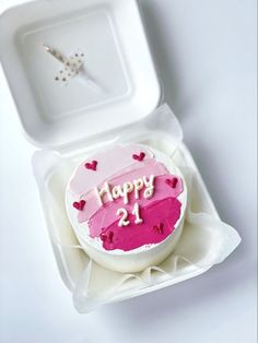 a birthday cake with pink icing and hearts on it in a white box, ready to be eaten