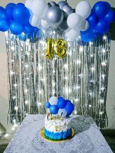 a blue and white birthday cake on a table with balloons in the shape of numbers