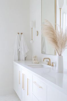 a white bathroom with gold accents and mirrors