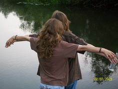 two people are standing in the water with their arms around each other's shoulders