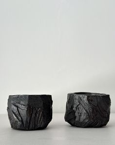 two black vases sitting next to each other on a table