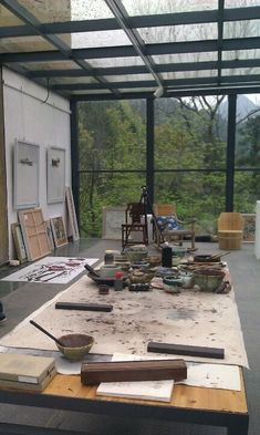 the table is covered with art supplies and other items in front of a large glass window