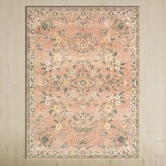 an orange and beige rug with floral designs on the bottom, in front of a wooden wall