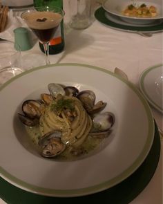 a plate of pasta with clams and sauce on the side at a restaurant table