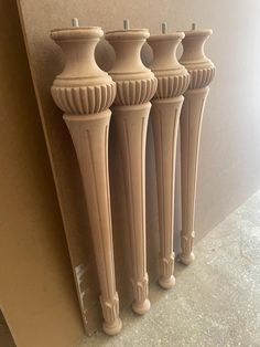 three white vases are lined up against the wall