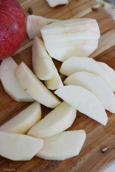 sliced apples on a cutting board with an apple in the background