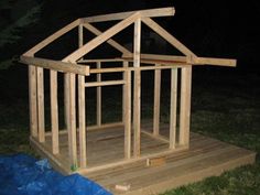 a small house made out of wood sitting on top of a wooden platform in the grass