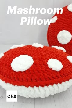 two red and white knitted mushrooms sitting on top of each other with the words mashroom pillow above them