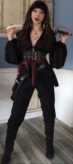 a woman dressed in pirate costume holding two wrenches and posing for the camera with one hand on her hip