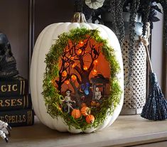 a pumpkin decorated with an image of a tree and skeletons is sitting on a mantle