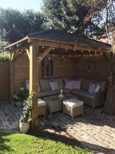 an outdoor living area with couches, tables and lights on the side of it