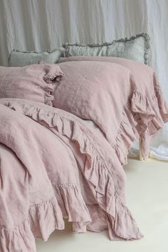 a bed with pink linens and ruffled pillows